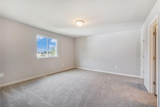 carpeted spare room featuring visible vents and baseboards