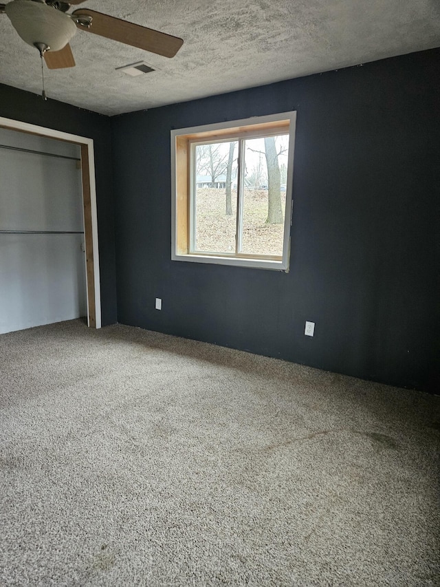 unfurnished bedroom featuring ceiling fan, a closet, carpet, and a textured ceiling