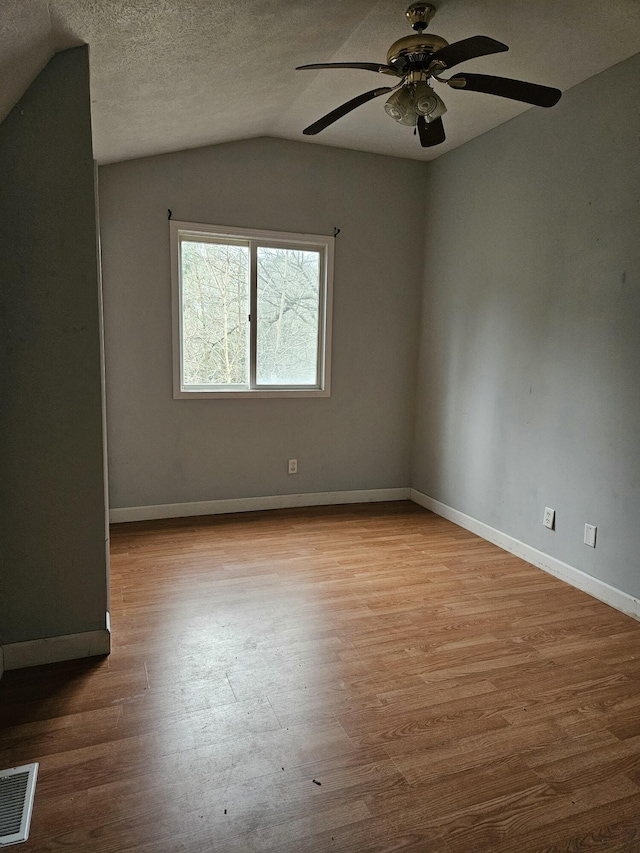 spare room featuring a textured ceiling, light hardwood / wood-style floors, ceiling fan, and lofted ceiling