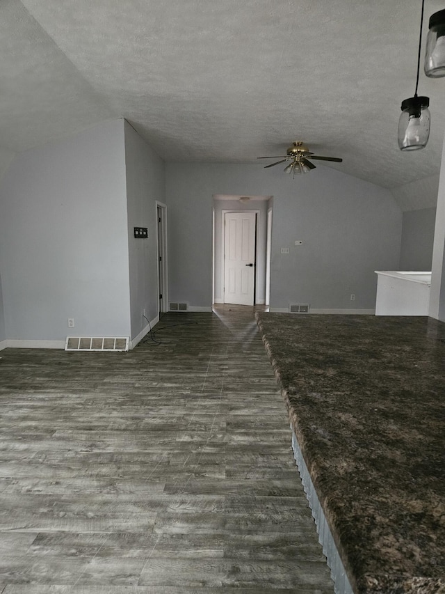 unfurnished living room featuring a textured ceiling, dark hardwood / wood-style floors, ceiling fan, and lofted ceiling