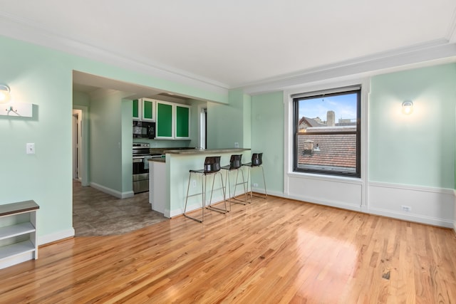 kitchen featuring kitchen peninsula, crown molding, stainless steel electric stove, a breakfast bar, and green cabinetry