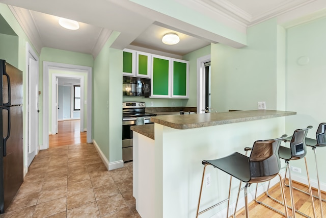 kitchen featuring kitchen peninsula, a kitchen bar, crown molding, and black appliances