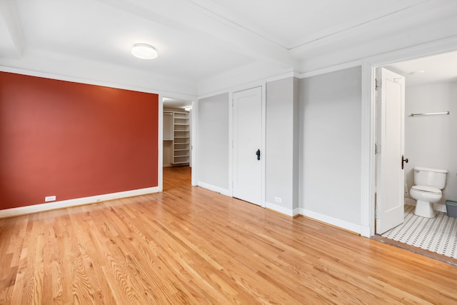 unfurnished bedroom with ensuite bathroom and light hardwood / wood-style floors