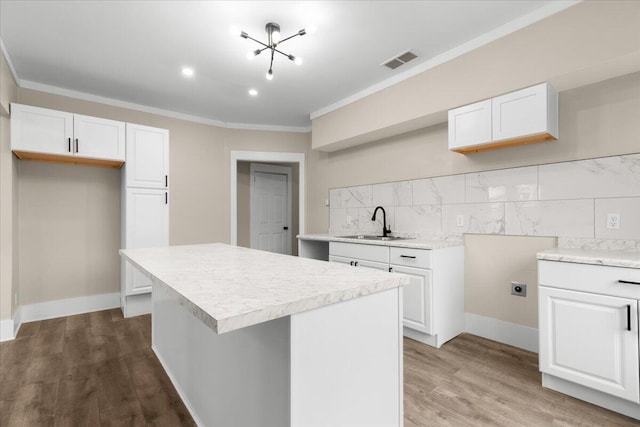 kitchen featuring white cabinets, a center island, and sink