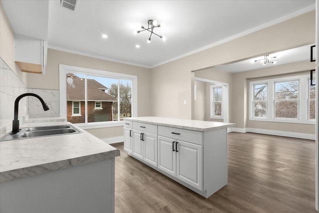 kitchen featuring hardwood / wood-style floors, backsplash, white cabinets, sink, and a kitchen island