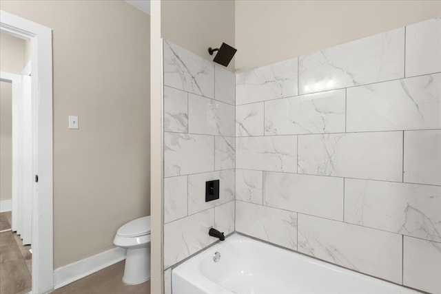 bathroom featuring tiled shower / bath combo and toilet