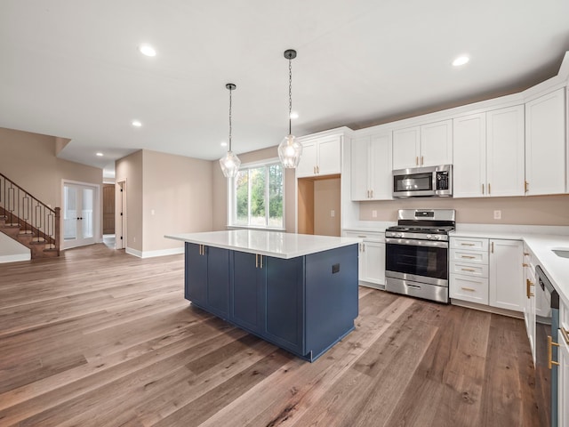 kitchen featuring white cabinets, appliances with stainless steel finishes, a center island, and hanging light fixtures