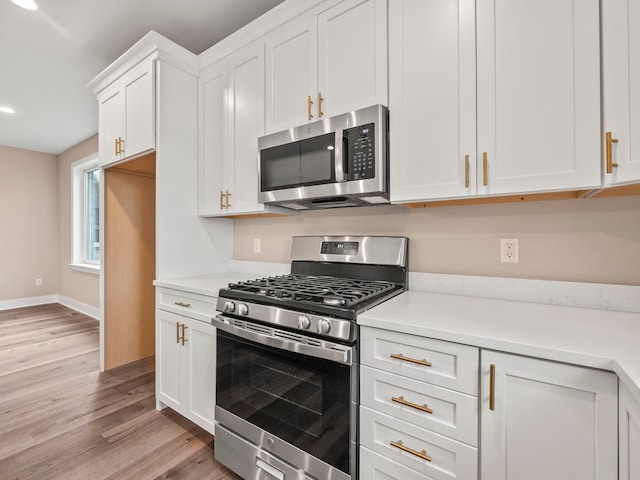 kitchen with light hardwood / wood-style flooring, white cabinets, and stainless steel appliances