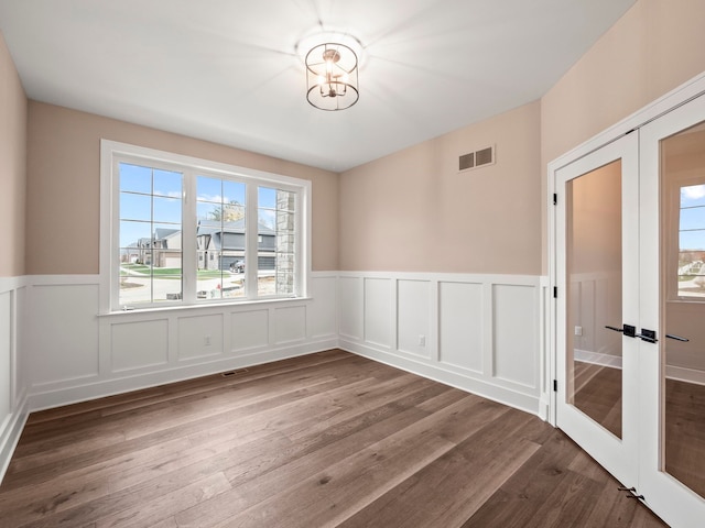 empty room featuring a chandelier, french doors, and wood-type flooring