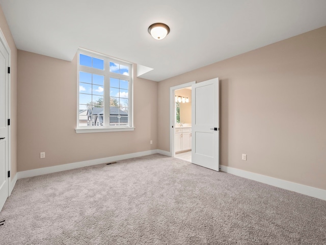 unfurnished bedroom with ensuite bathroom and light colored carpet