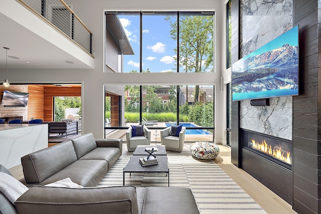 living room with a fireplace, a high ceiling, light hardwood / wood-style flooring, and plenty of natural light