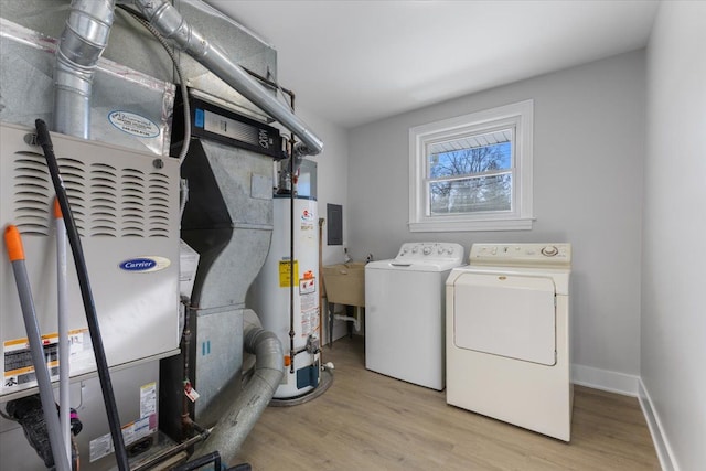 washroom featuring gas water heater, sink, washer and dryer, light hardwood / wood-style floors, and heating unit