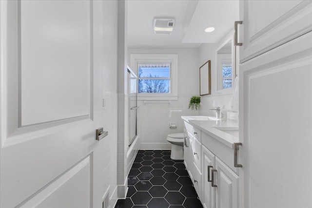 bathroom featuring vanity, toilet, and tile walls