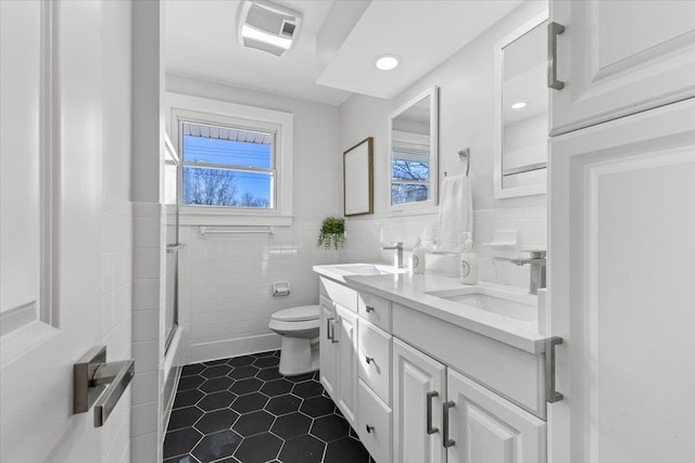 full bathroom featuring vanity, toilet, tile walls, and enclosed tub / shower combo