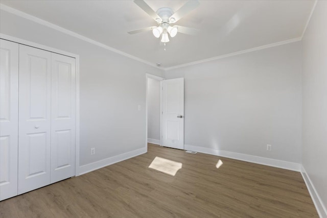 unfurnished bedroom featuring hardwood / wood-style floors, ceiling fan, ornamental molding, and a closet