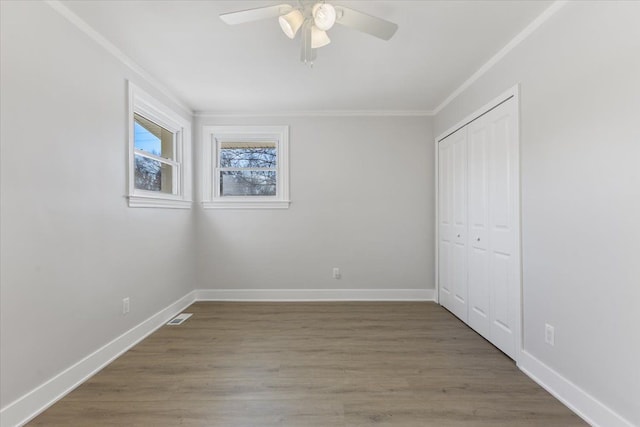 unfurnished bedroom featuring ceiling fan, wood-type flooring, crown molding, and a closet