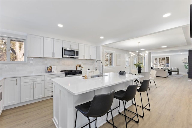 kitchen with sink, a center island with sink, white cabinets, and appliances with stainless steel finishes