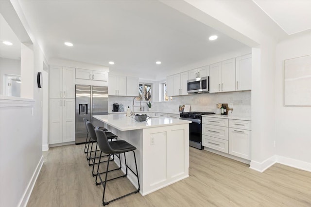 kitchen featuring a kitchen island, white cabinetry, stainless steel appliances, and a breakfast bar area