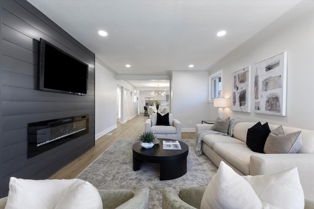 living room featuring a large fireplace, light hardwood / wood-style floors, and a chandelier