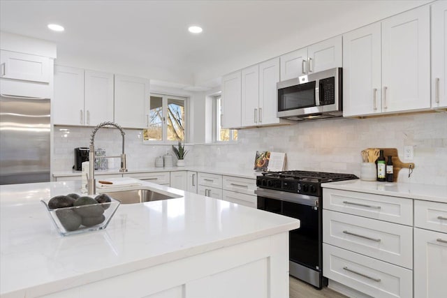 kitchen with appliances with stainless steel finishes, tasteful backsplash, white cabinetry, and sink