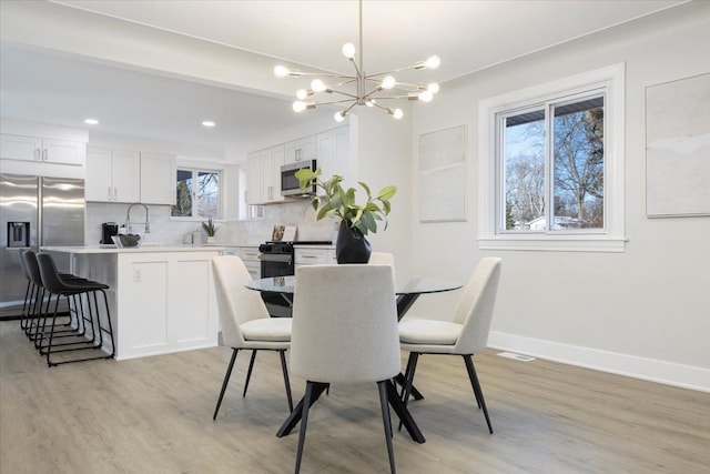 dining room featuring light hardwood / wood-style flooring, a wealth of natural light, and a notable chandelier