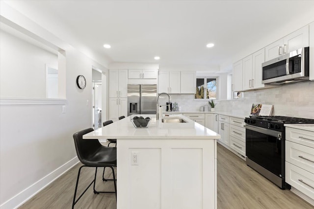 kitchen with white cabinets, sink, an island with sink, a kitchen bar, and stainless steel appliances