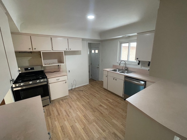 kitchen with stainless steel appliances, a sink, light countertops, and white cabinets