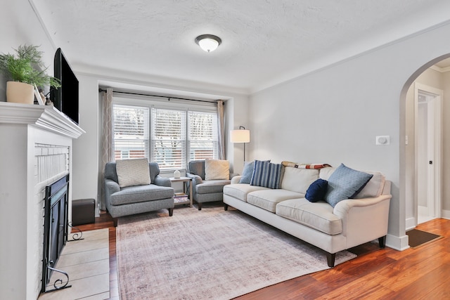 living room featuring hardwood / wood-style floors, crown molding, a fireplace, and a textured ceiling