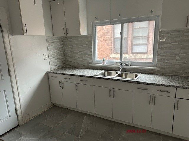 kitchen featuring backsplash, sink, white cabinets, and tile patterned flooring