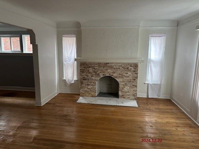 unfurnished living room featuring hardwood / wood-style floors, a stone fireplace, and a wealth of natural light