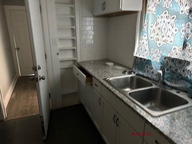 kitchen featuring sink, light stone counters, dark hardwood / wood-style floors, decorative backsplash, and white cabinets