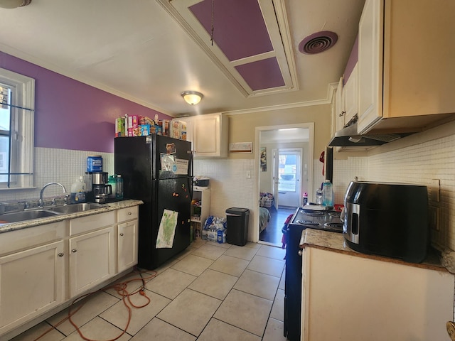 kitchen with stove, black refrigerator, sink, light tile patterned floors, and ornamental molding