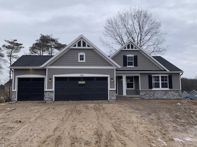 craftsman inspired home featuring board and batten siding, stone siding, an attached garage, and dirt driveway