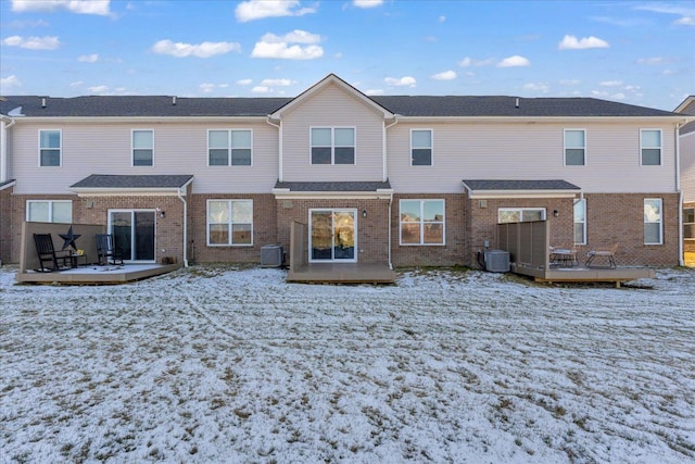 snow covered house with central AC and a deck