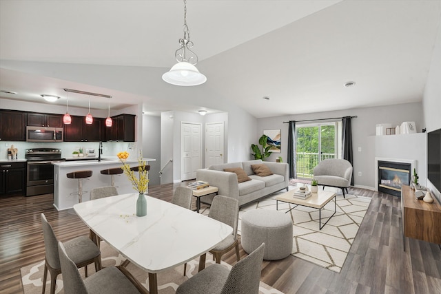 dining space with sink, dark wood-type flooring, and vaulted ceiling