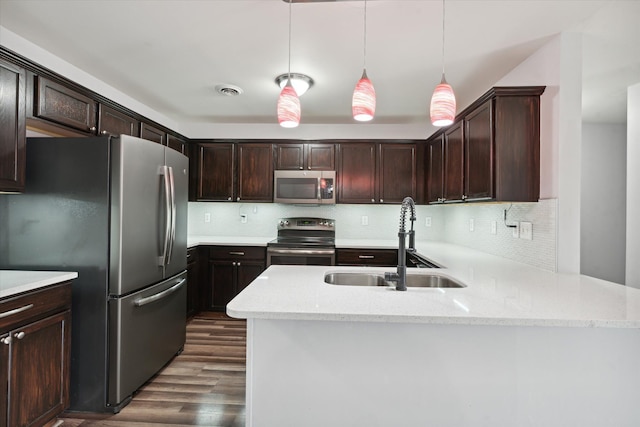 kitchen featuring pendant lighting, light stone counters, sink, and stainless steel appliances