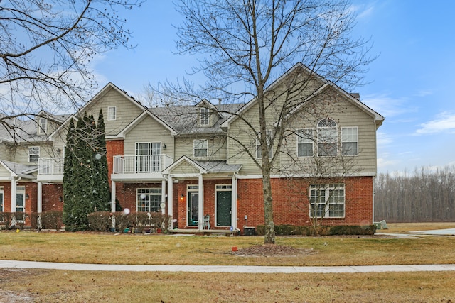 view of front of house featuring a balcony and a front lawn