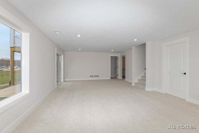 empty room with recessed lighting, baseboards, light carpet, and stairway