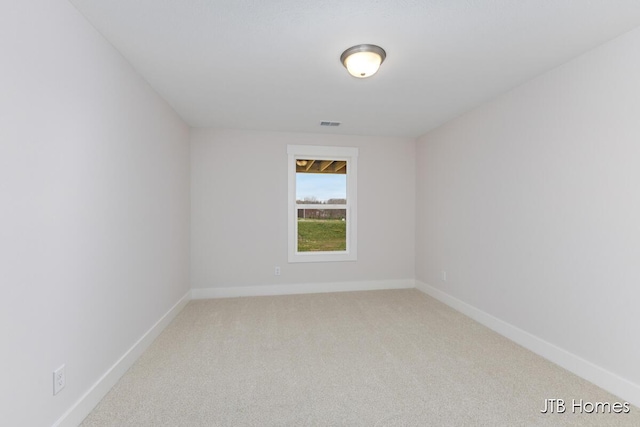 empty room with baseboards, visible vents, and light carpet