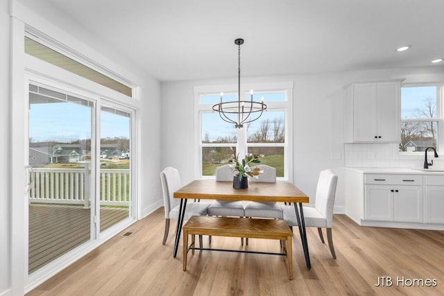 dining space featuring a wealth of natural light, light wood-type flooring, and a notable chandelier