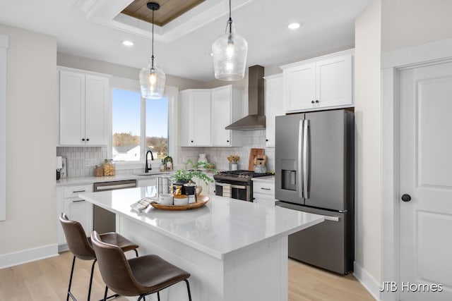 kitchen featuring a sink, tasteful backsplash, white cabinetry, stainless steel appliances, and wall chimney exhaust hood