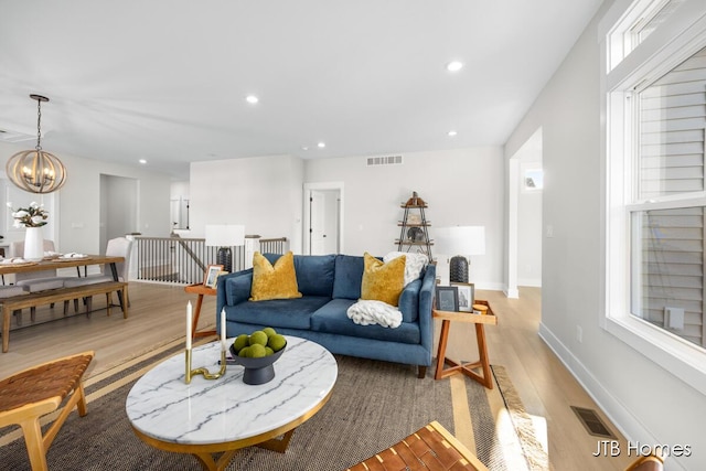 living area featuring baseboards, visible vents, light wood-style flooring, recessed lighting, and a chandelier