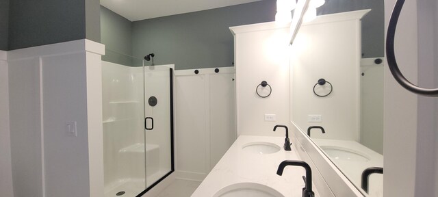 bathroom featuring double vanity, a stall shower, and a sink