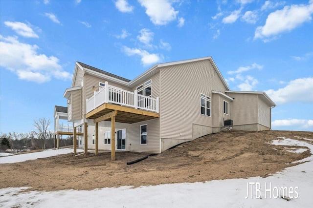 snow covered house with central AC unit and a deck