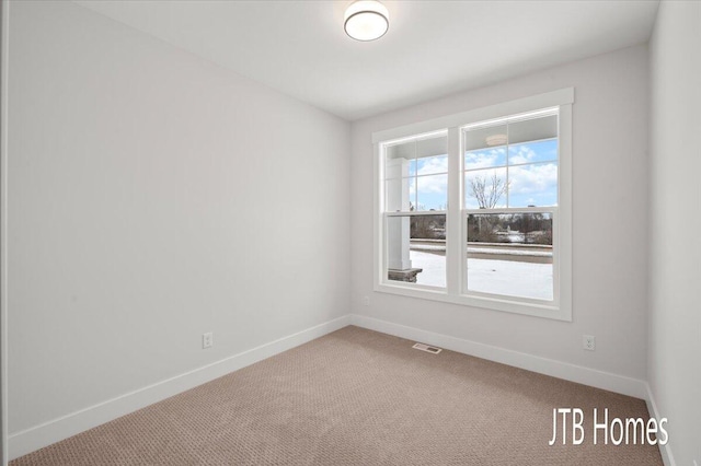 carpeted spare room featuring visible vents and baseboards