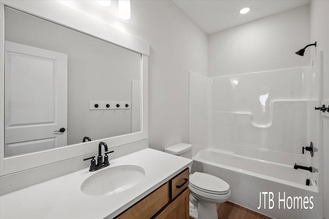 bathroom with vanity, toilet, wood finished floors, and  shower combination