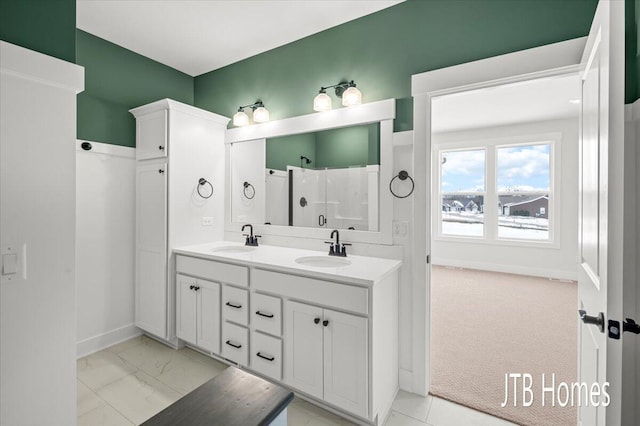 bathroom featuring double vanity, marble finish floor, a walk in shower, and a sink