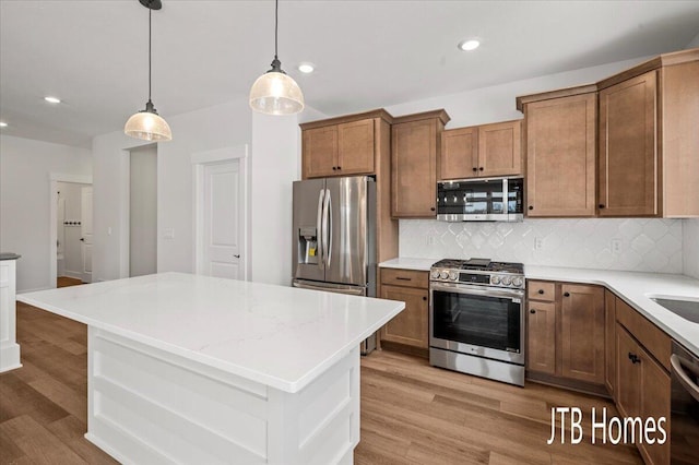 kitchen with decorative backsplash, light wood-style flooring, appliances with stainless steel finishes, and brown cabinets