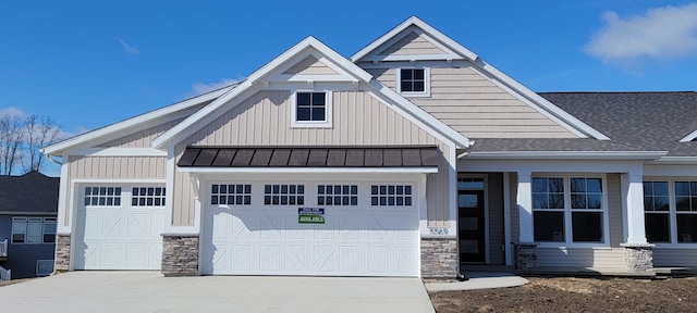 view of front of home with stone siding, an attached garage, driveway, and board and batten siding