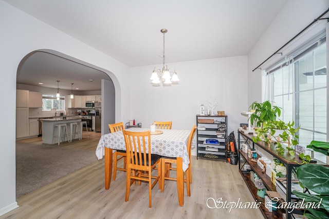 5337 Division Ave N, Comstock Park, MI 49321 - dining area featuring arched walkways, light wood-style flooring, and a chandelier